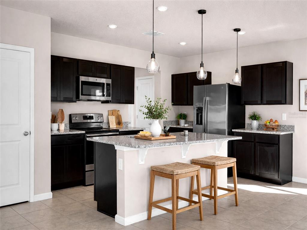 A kitchen with dark cabinets, granite countertops, stainless steel appliances, and a central island — 718 EAGLE LANDING BOULEVARD, WINTER HAVEN, FL