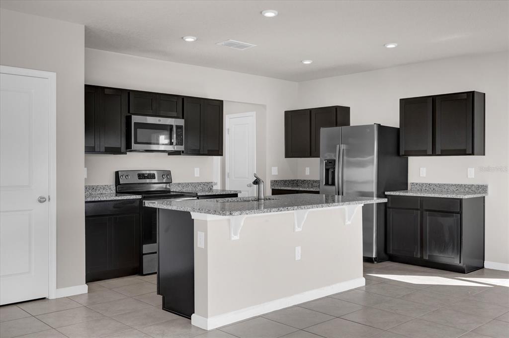 A kitchen features dark cabinets, granite countertops, a center island, and stainless steel appliances — 718 EAGLE LANDING BOULEVARD, WINTER HAVEN, FL