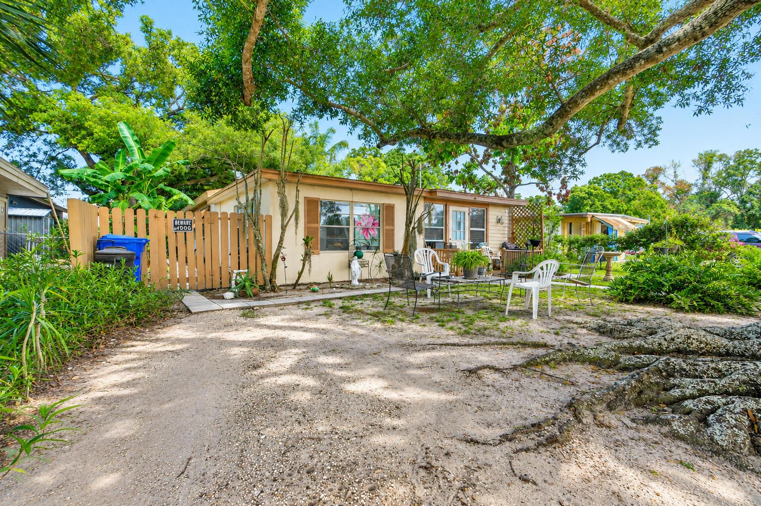 A single-story house with a sandy yard, patio furniture, and a wooden fence under trees — 2666 12th Avenue, Vero Beach FL 32960, VERO BEACH, FL