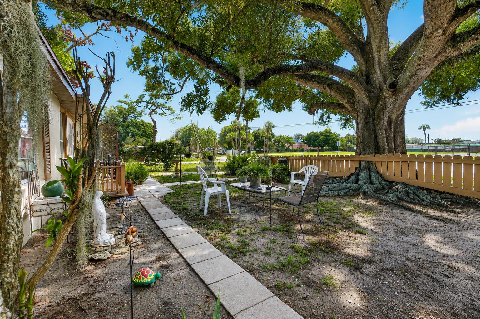 A backyard patio features a large tree, a stone walkway, and outdoor seating — 2666 12th Avenue, Vero Beach FL 32960, VERO BEACH, FL