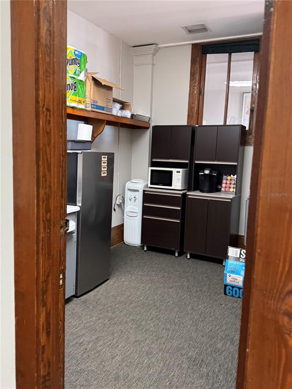 A small break room features a refrigerator, dark cabinets, a microwave, and a water cooler — 44 SE 1ST AVENUE, OCALA, FL