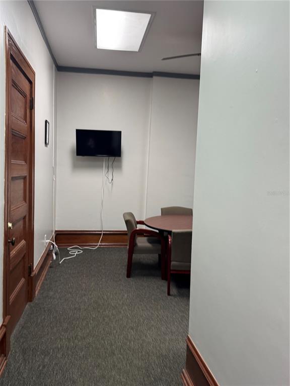 A small office room features a round table, chairs, a wall-mounted television, and wood trim — 44 SE 1ST AVENUE, OCALA, FL