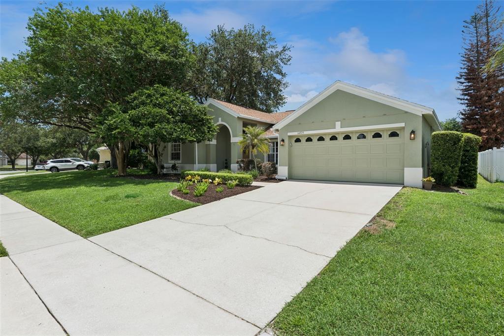 A single-story house with a light green exterior, a two-car garage, and a concrete driveway — 14975 FAVERSHAM CIRCLE, ORLANDO, FL