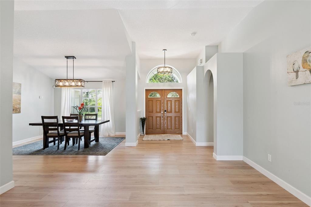 A dining area with a wooden table sits beside a foyer with double front doors — 14975 FAVERSHAM CIRCLE, ORLANDO, FL