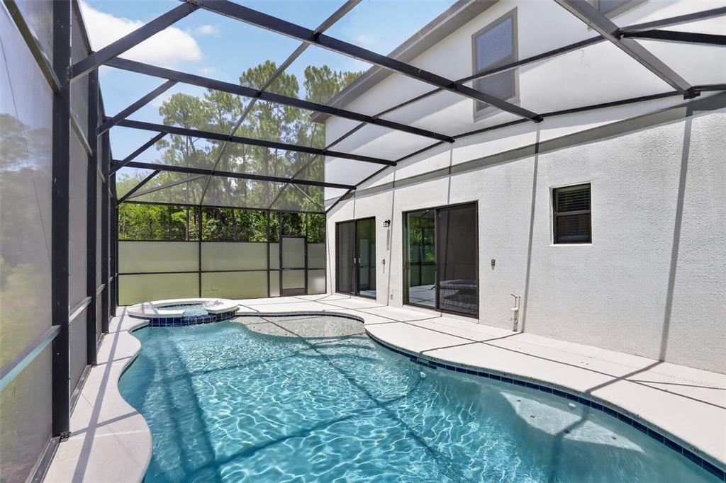 A two-story house with a screened-in pool and patio area in a grassy backyard — 1242 BUTTERFLY ORCHID ROAD, DAVENPORT, FL