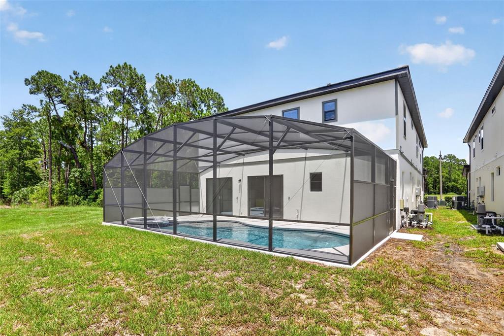 A backyard view of a two-story house with a screened-in pool and spa — 1242 BUTTERFLY ORCHID ROAD, DAVENPORT, FL
