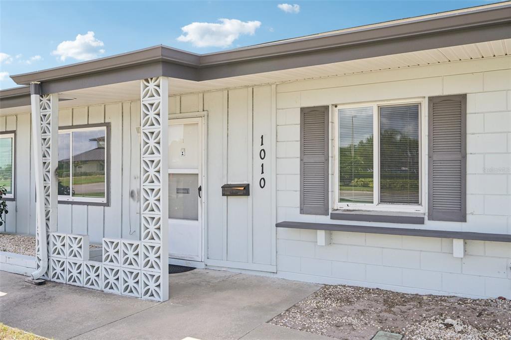 The exterior of a house features a decorative concrete block screen, a front door, and windows — 1010 N PEBBLE BEACH BOULEVARD, SUN CITY CENTER, FL