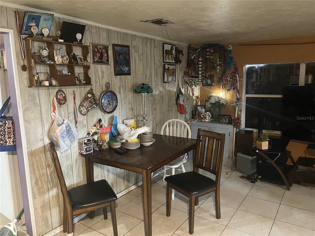 A dining area features wood-paneled walls, a dark wood table, and tiled flooring — 1127 AUBURN STREET, CLEARWATER, FL