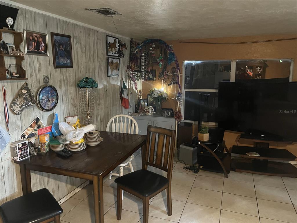A dining area features wood-paneled walls, a dark wood table, and tile flooring — 1127 AUBURN STREET, CLEARWATER, FL