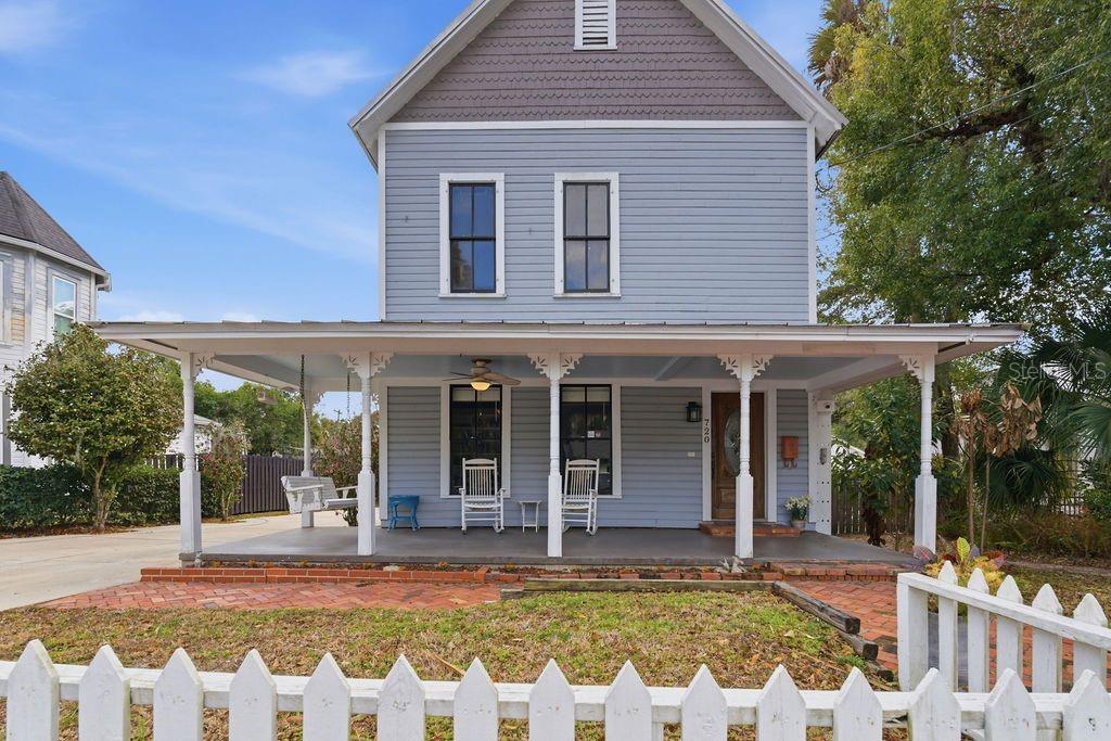 A two-story blue house features a wide front porch with white columns and a fence — 720 SE 3RD STREET, OCALA, FL