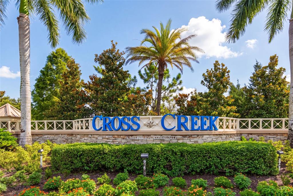 The entrance sign for Cross Creek community features blue lettering on a stone wall — 12627 WHEATGRASS COURT, PARRISH, FL
