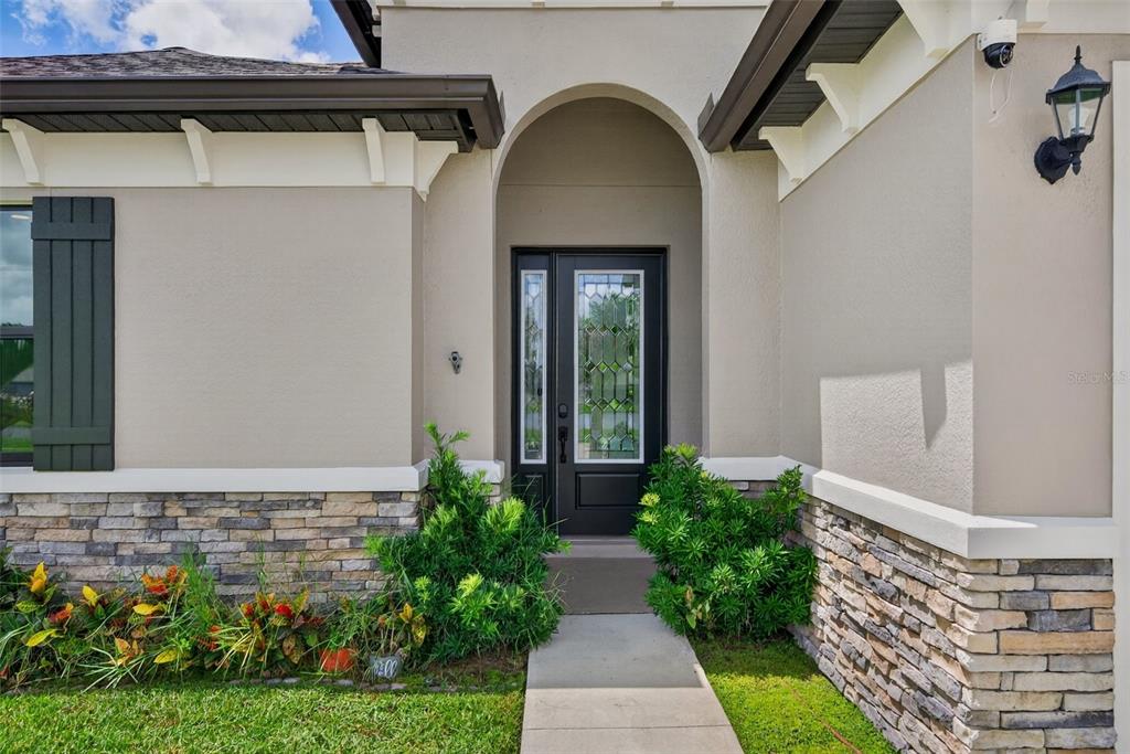 The exterior of a house features a stone-accented facade, a dark front door, and landscaping — 12627 WHEATGRASS COURT, PARRISH, FL