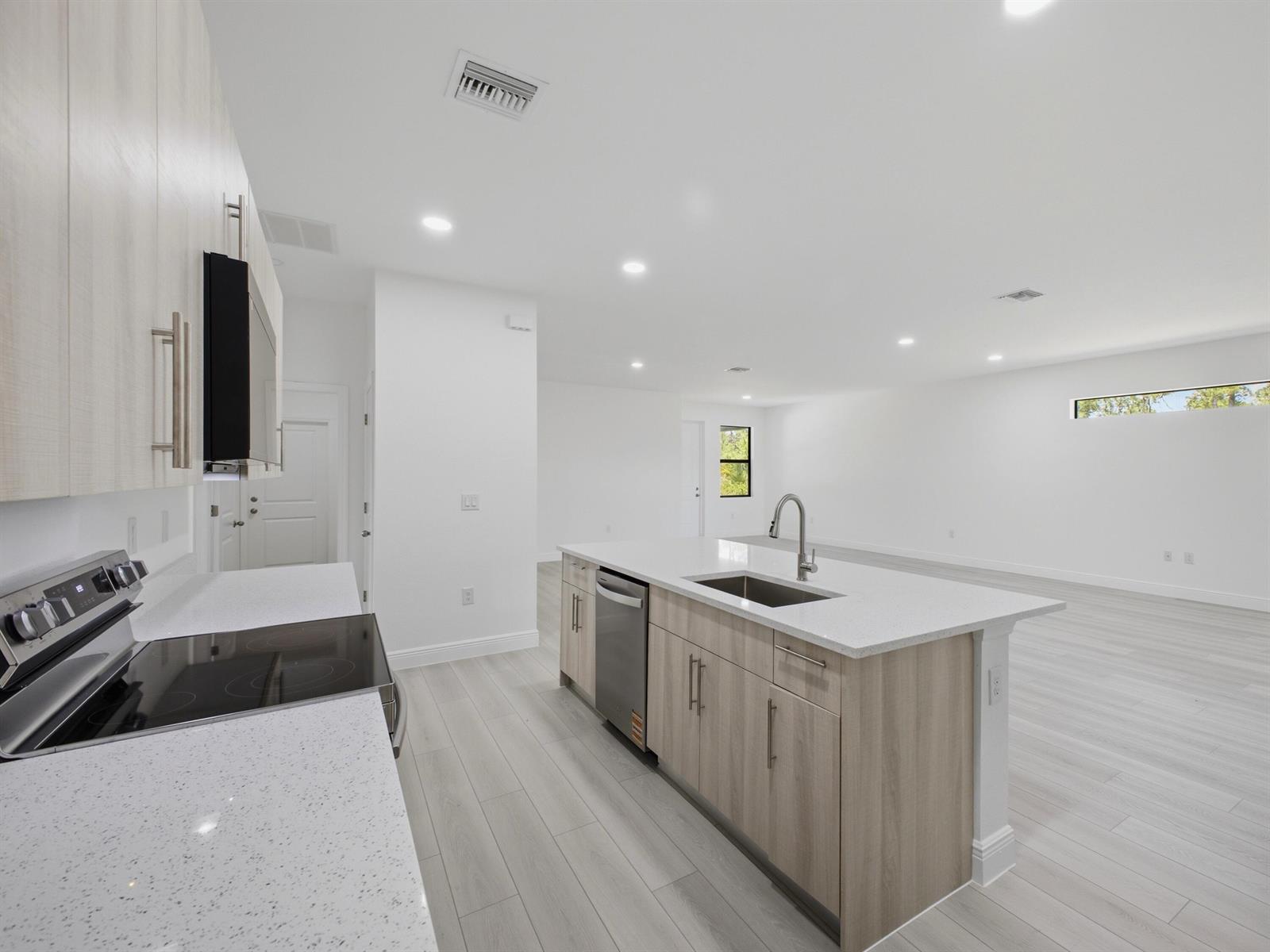 A modern kitchen features light wood cabinets, white quartz countertops, and a central island — 8010 Sandalwood Lane, FL 33935, FL