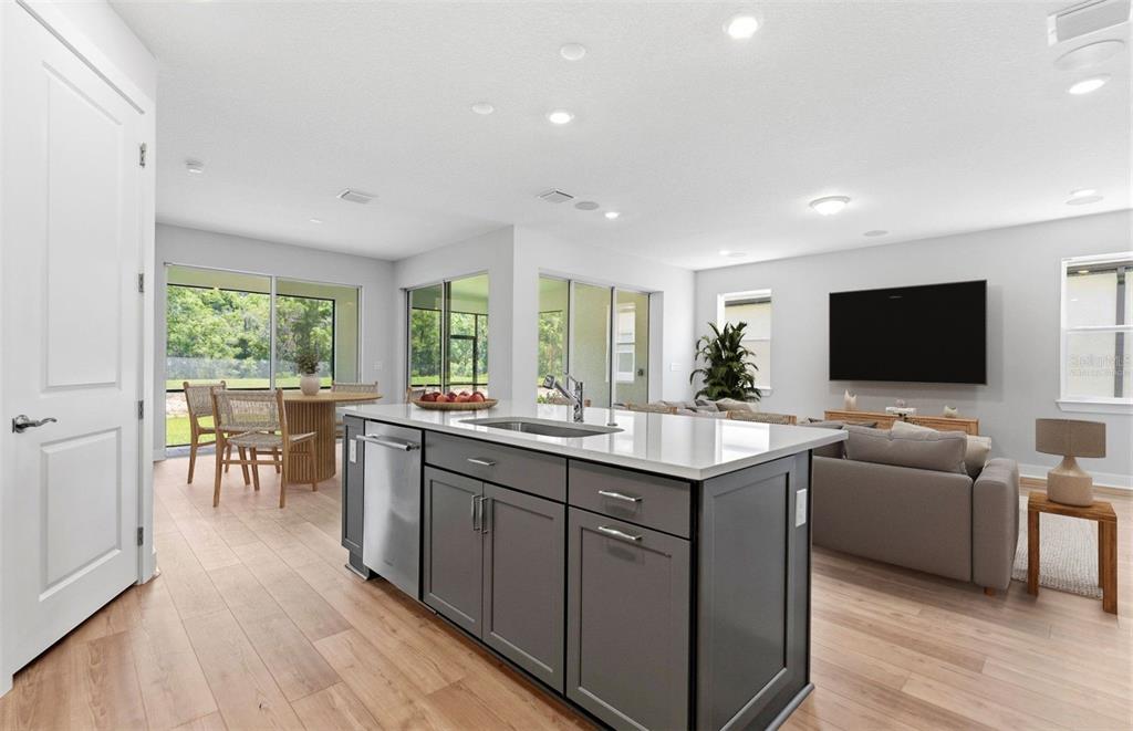A kitchen island with dark cabinets and a white countertop faces a living room area — 13504 CANYON RIDGE ROAD, SPRING HILL, FL
