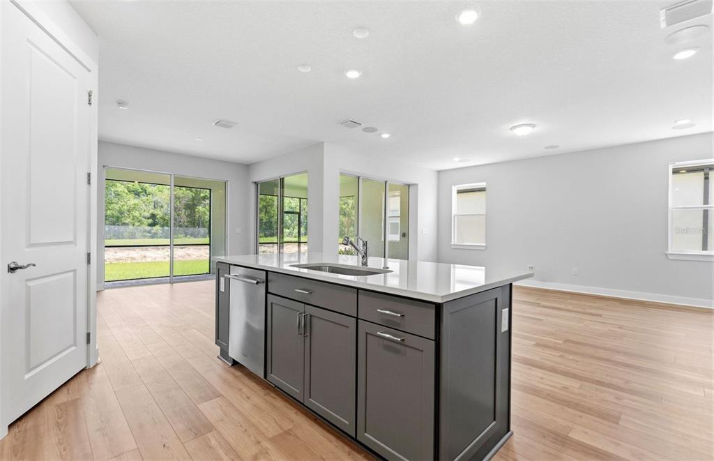 A kitchen island with dark gray cabinets and a white countertop sits in an open room — 13504 CANYON RIDGE ROAD, SPRING HILL, FL