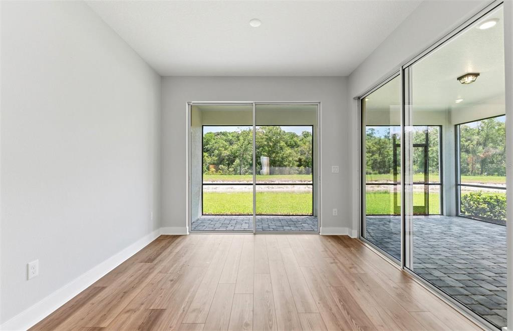 A room with light gray walls, wood-look flooring, and sliding glass doors leading to a patio — 13504 CANYON RIDGE ROAD, SPRING HILL, FL
