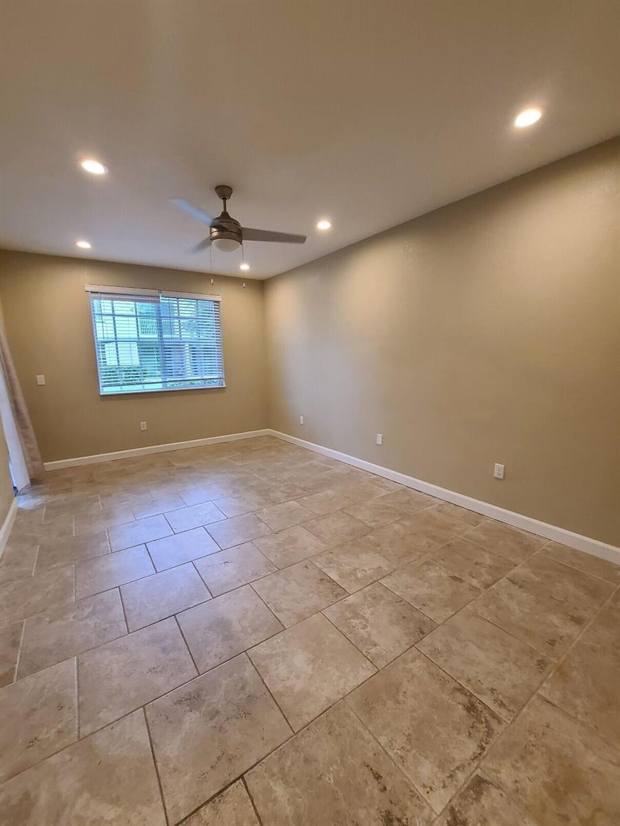 An empty room with beige walls, tile flooring, a ceiling fan, and a window — 1952 Flamingo Place, West Palm Beach FL 33404, WEST PALM BEACH, FL