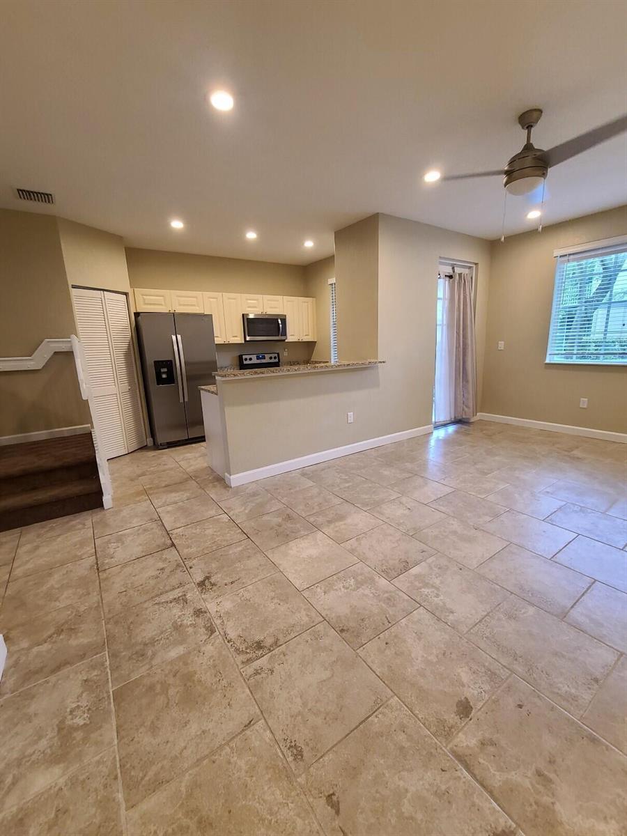 An open-concept kitchen with stainless steel appliances and tile flooring overlooks a living area — 1952 Flamingo Place, West Palm Beach FL 33404, WEST PALM BEACH, FL