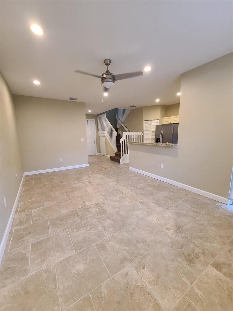 An open-concept living area features beige tile flooring, recessed lighting, and a staircase with railings — 1952 Flamingo Place, West Palm Beach FL 33404, WEST PALM BEACH, FL