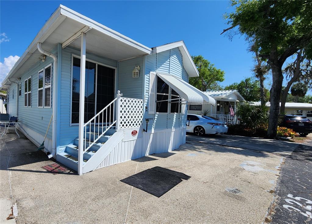 A light blue mobile home with a white staircase and an attached metal awning — 3300 26TH AVENUE E UNIT 225, BRADENTON, FL