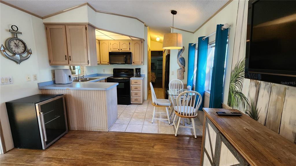 A kitchen and dining area features light wood cabinets, a breakfast bar, and tile flooring — 3300 26TH AVENUE E UNIT 225, BRADENTON, FL