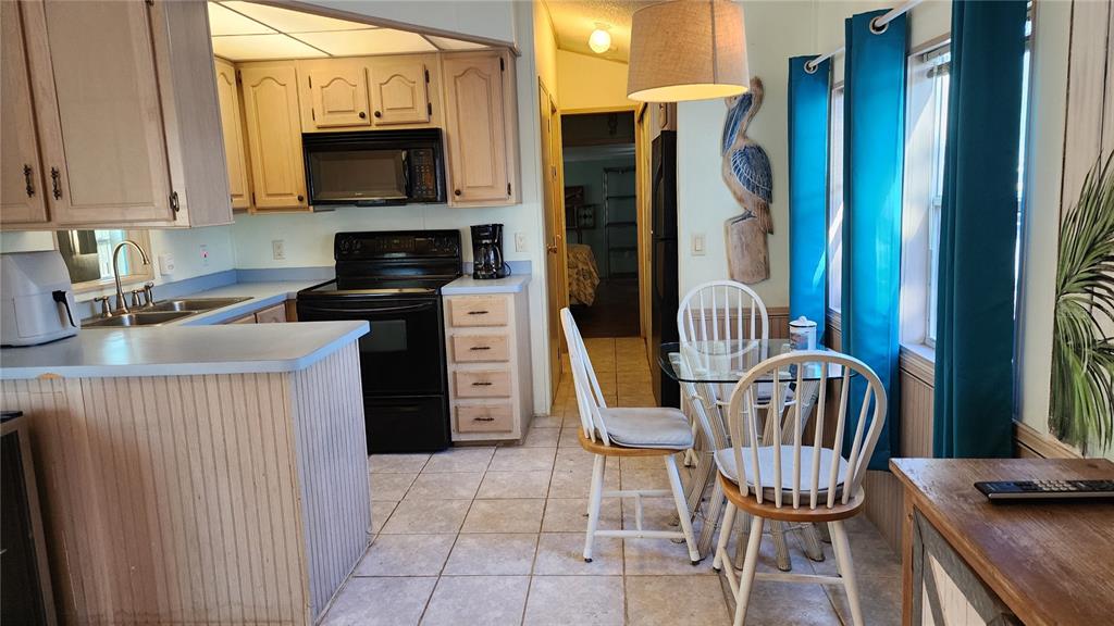A kitchen with light wood cabinets, black appliances, and a small dining area with chairs — 3300 26TH AVENUE E UNIT 225, BRADENTON, FL