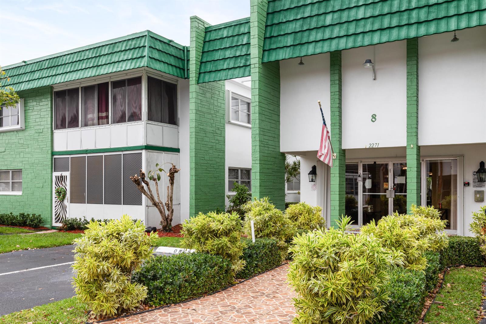 The exterior of a two-story building features green roof tiles, white walls, and landscaping — 2271 NW 48th Terrace # 111, Lauderhill FL 33313, LAUDERHILL, FL