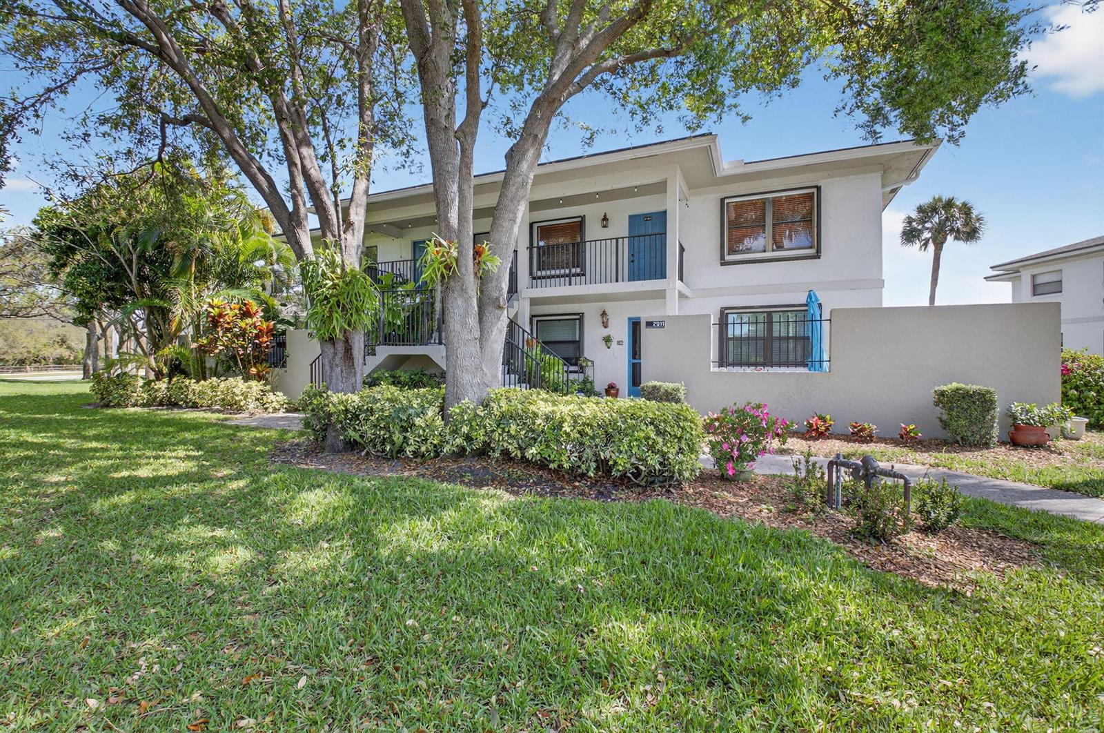 A two-story apartment building with a balcony, blue doors, and a landscaped front yard — 2911 SW 21st Terrace # 272b, Delray Beach FL 33445, DELRAY BEACH, FL