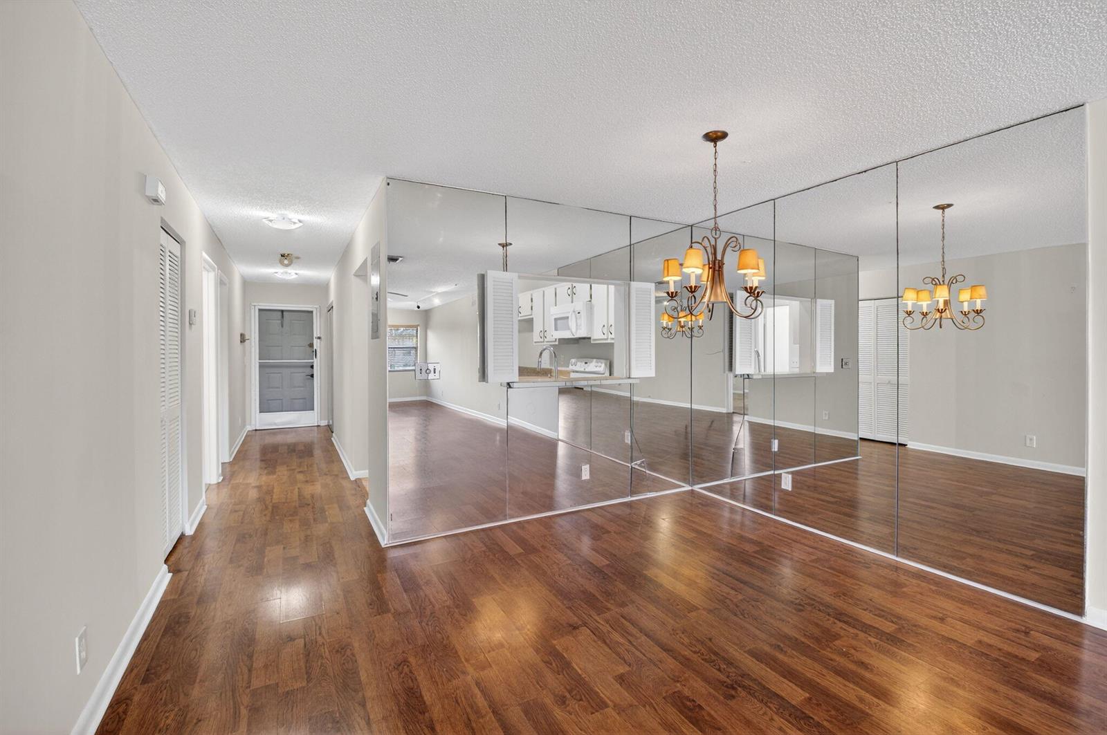 A dining area with wood flooring, a chandelier, and a large mirrored wall — 2911 SW 21st Terrace # 272b, Delray Beach FL 33445, DELRAY BEACH, FL