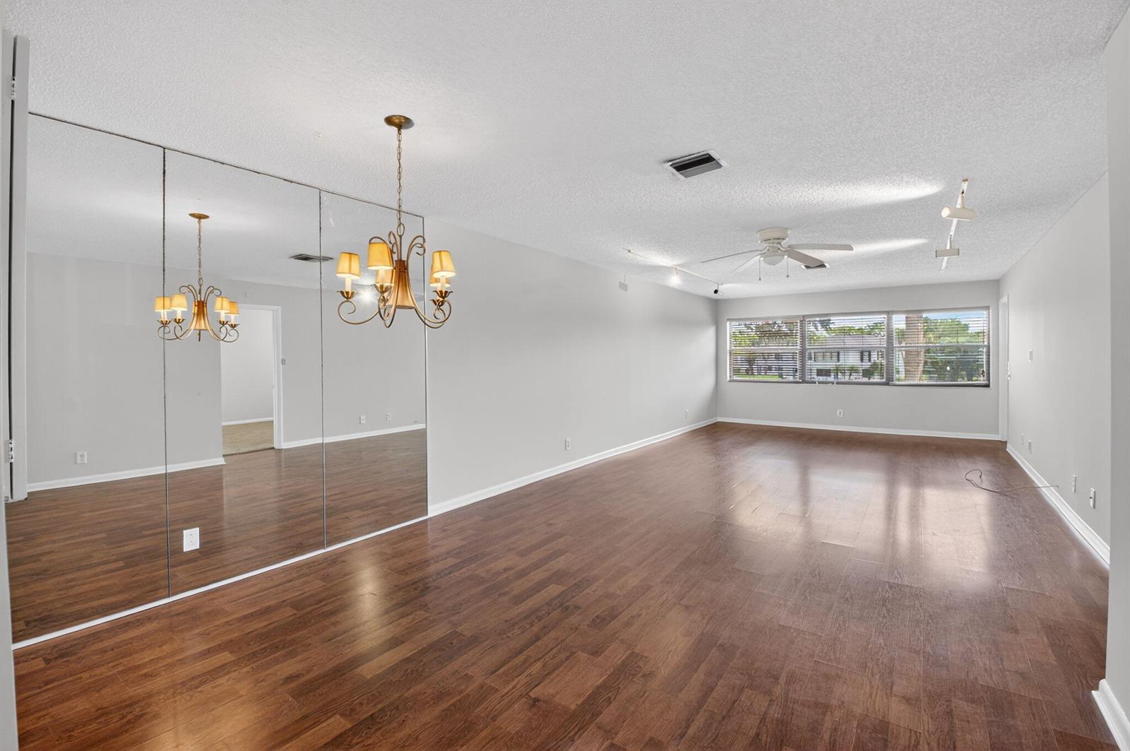A spacious living room features dark wood flooring, a mirrored wall, and a ceiling fan — 2911 SW 21st Terrace # 272b, Delray Beach FL 33445, DELRAY BEACH, FL