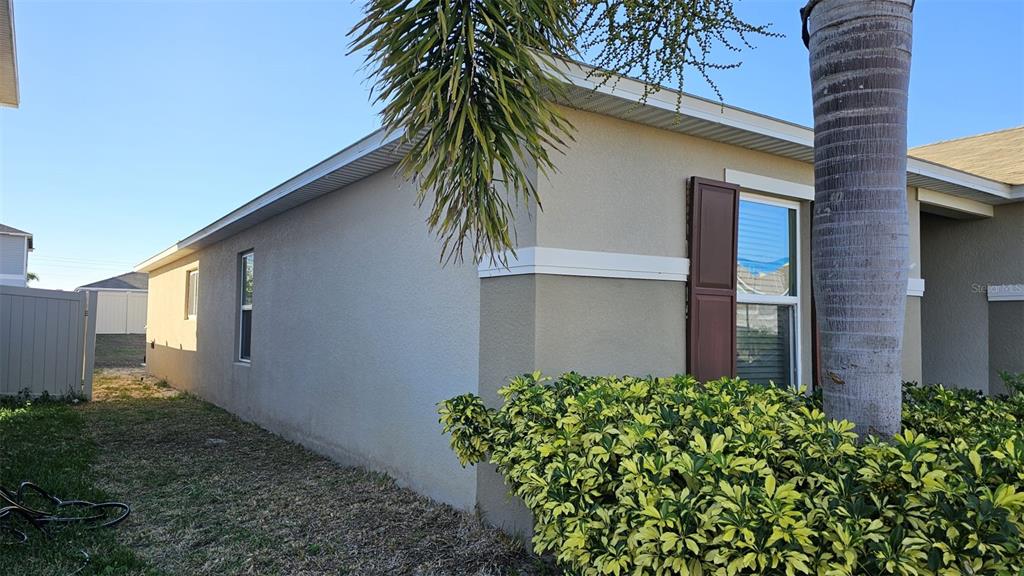 A side view of a beige stucco house with a palm tree and landscaping — 308 LAKE LUCERNE WAY, WINTER HAVEN, FL