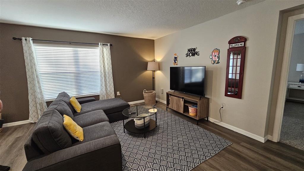 A living room features a grey sectional sofa, a television on a stand, and patterned rug — 308 LAKE LUCERNE WAY, WINTER HAVEN, FL