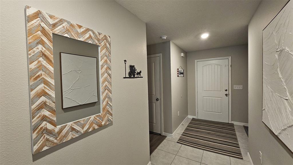 An entryway features a chevron-patterned mirror, a striped rug, and a white front door — 308 LAKE LUCERNE WAY, WINTER HAVEN, FL