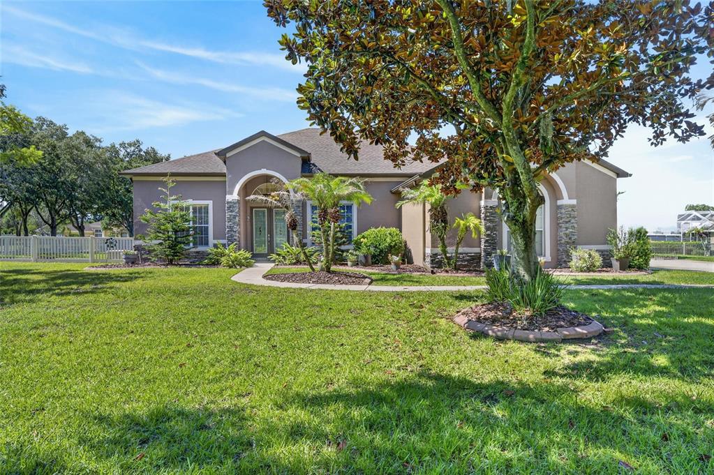 A single-story house with a tan stucco exterior, stone accents, and a large front yard — 209 FOREST BREEZE AVENUE, BRANDON, FL