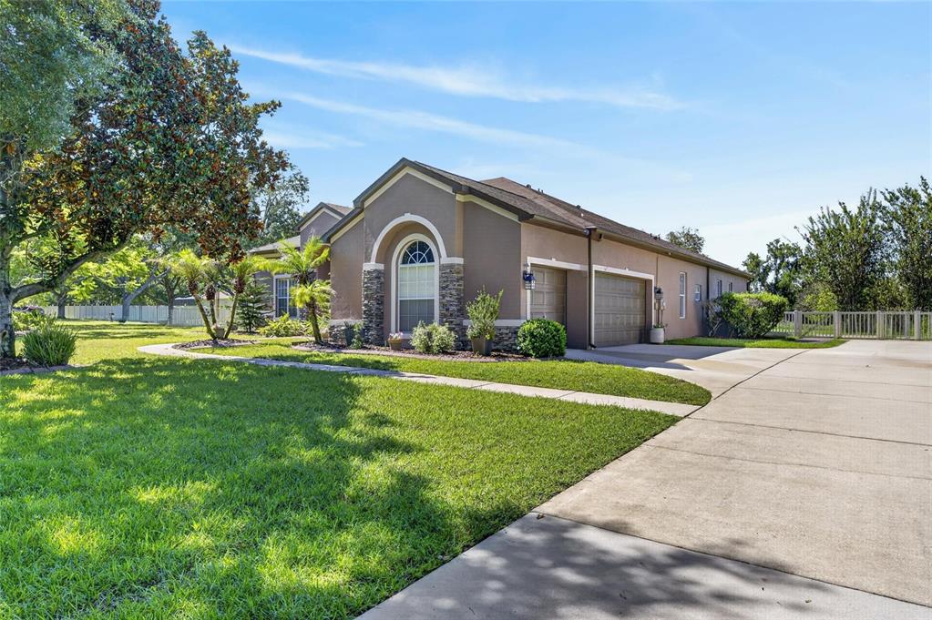 A single-story house with a tan stucco exterior, stone accents, and a concrete driveway — 209 FOREST BREEZE AVENUE, BRANDON, FL
