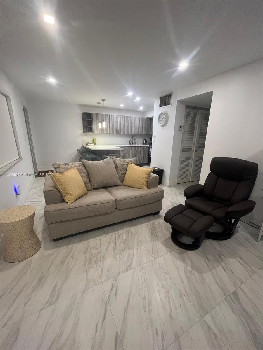 A living room features a beige sofa, a dark recliner, and an open kitchen area — 2145 Pierce St # 422, Hollywood FL 33020, HOLLYWOOD, FL