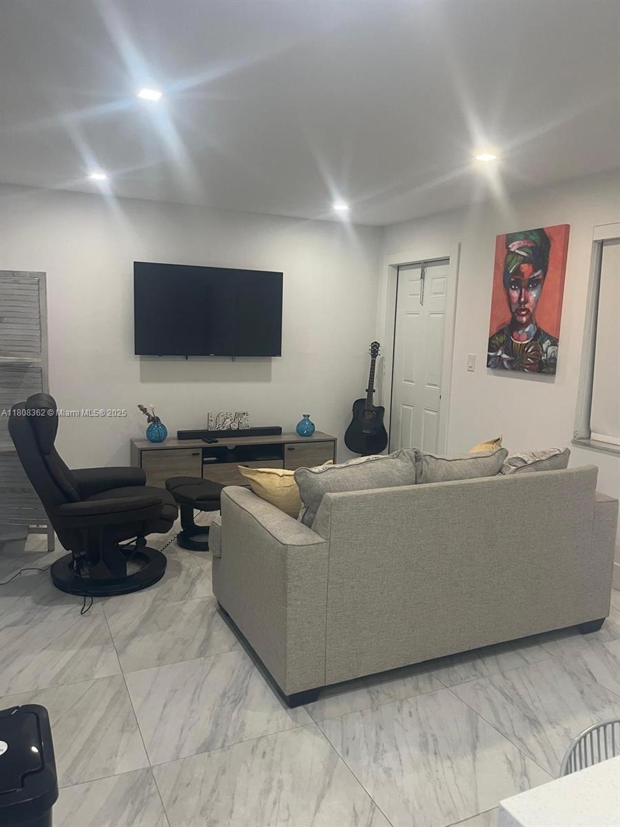A living room features a grey sofa, a recliner, a wall-mounted television, and tile flooring — 2145 Pierce St # 422, Hollywood FL 33020, HOLLYWOOD, FL