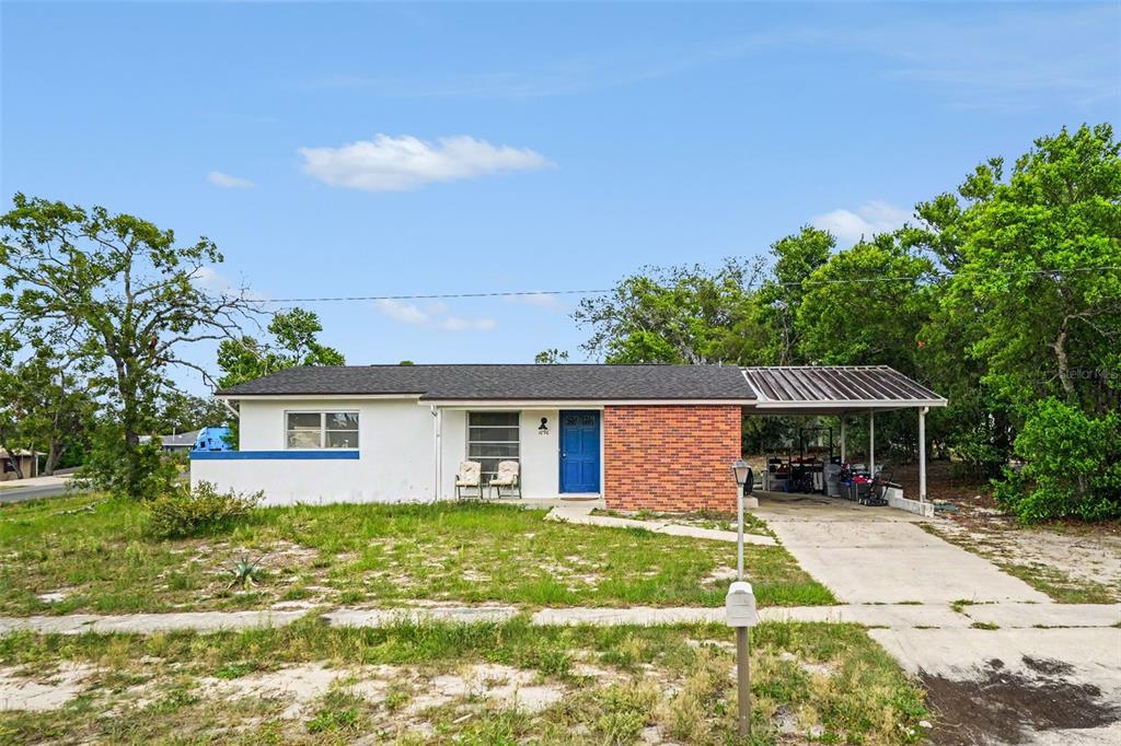 A single-story house with a white exterior, brick facade, blue front door, and attached carport — 1096 MARLOW AVENUE, SPRING HILL, FL
