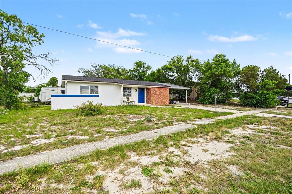A single-story house with white siding, a brick accent wall, and a blue front door — 1096 MARLOW AVENUE, SPRING HILL, FL