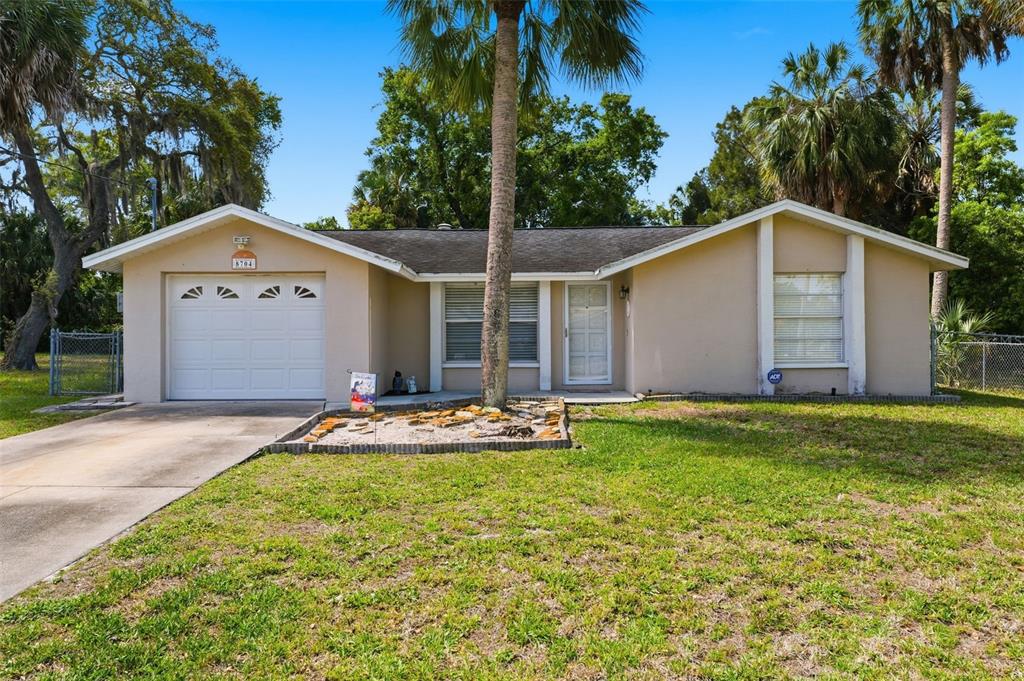 A single-story house with a beige exterior, a one-car garage, and a palm tree — 8704 LONG BOAT LANE, HUDSON, FL