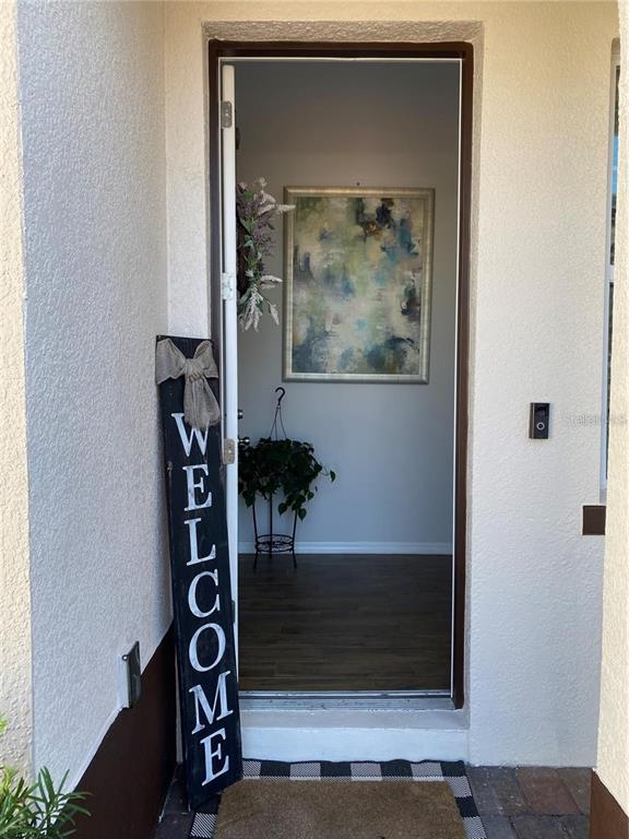 A view through an open doorway shows an entryway with wood flooring and wall art — 5416 CARRARA COURT, ST CLOUD, FL