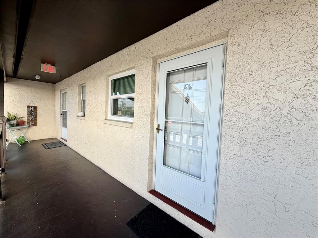 An exterior view of a building walkway with a white door labeled 202 — 4807 MARINE PARKWAY UNIT 202, NEW PORT RICHEY, FL
