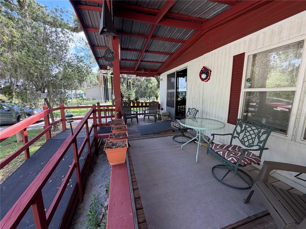 A covered porch features a wheelchair ramp, outdoor seating, and potted plants — 3315 CR 431N, LAKE PANASOFFKEE, FL