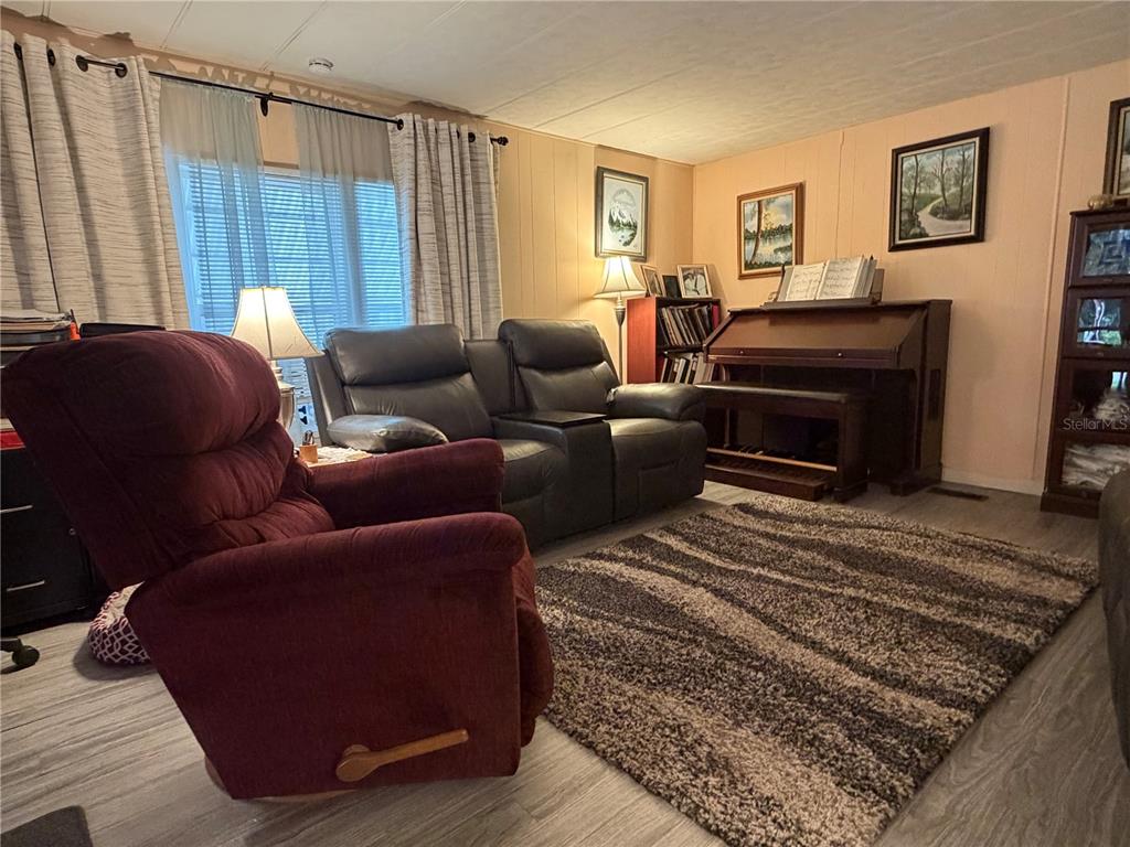 A living room features a maroon recliner, a dark leather loveseat, and an upright piano — 3315 CR 431N, LAKE PANASOFFKEE, FL