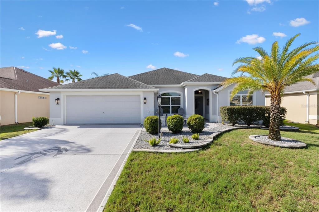 A single-story house with a two-car garage, a palm tree, and a landscaped front yard — 3461 EARL WAY, THE VILLAGES, FL
