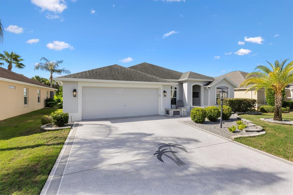 A single-story house with a white garage, a palm tree stencil, and a landscaped front yard — 3461 EARL WAY, THE VILLAGES, FL
