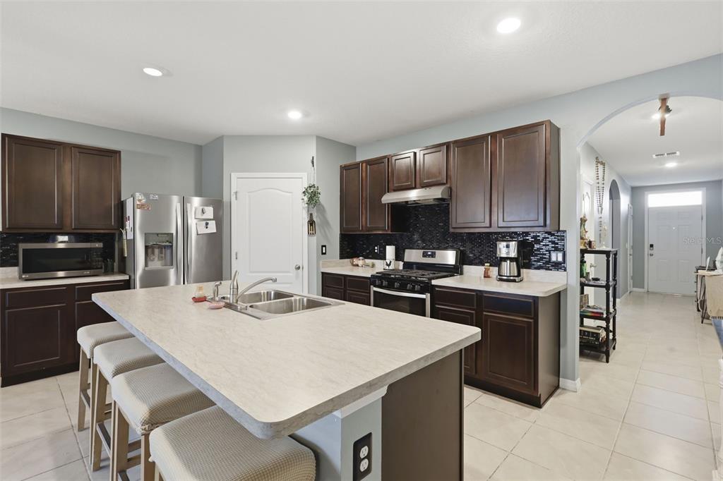 A kitchen with dark wood cabinets, a large island, and light-colored countertops — 3871 BRANT PLACE, LEESBURG, FL