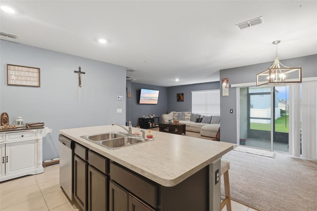 A kitchen island with a double sink overlooks an open-concept living room with a sofa — 3871 BRANT PLACE, LEESBURG, FL