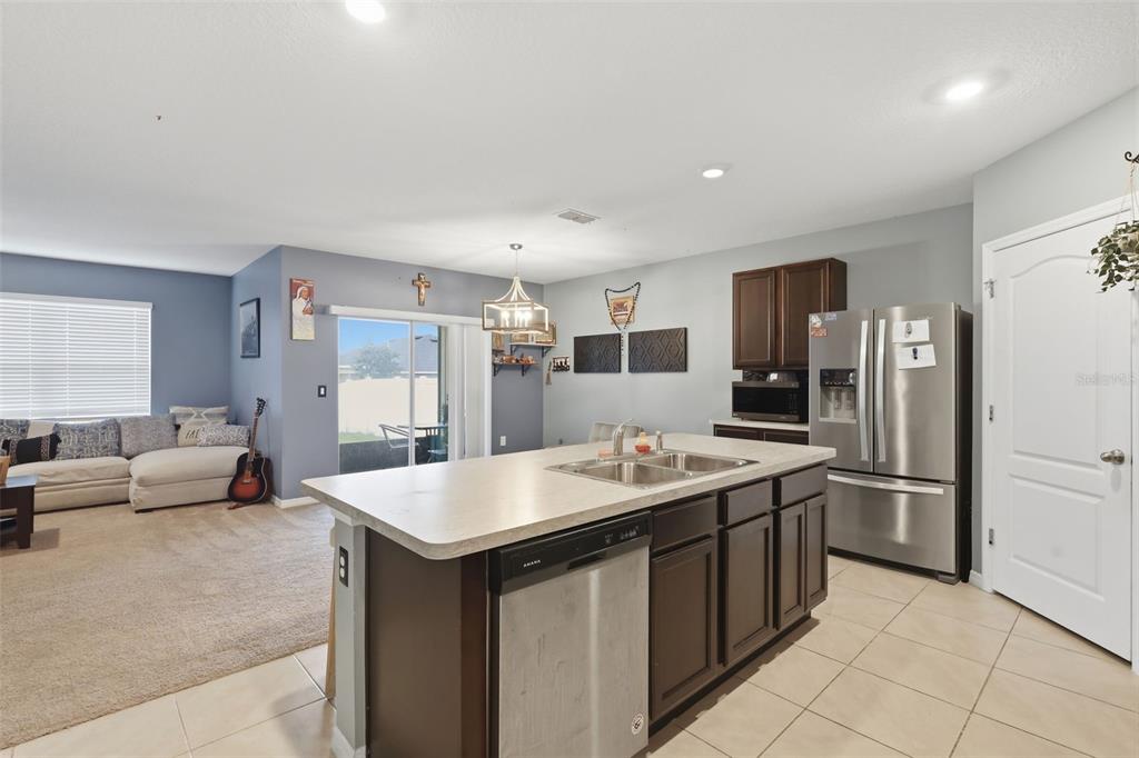 A kitchen with a center island and stainless steel appliances opens into a carpeted living area — 3871 BRANT PLACE, LEESBURG, FL