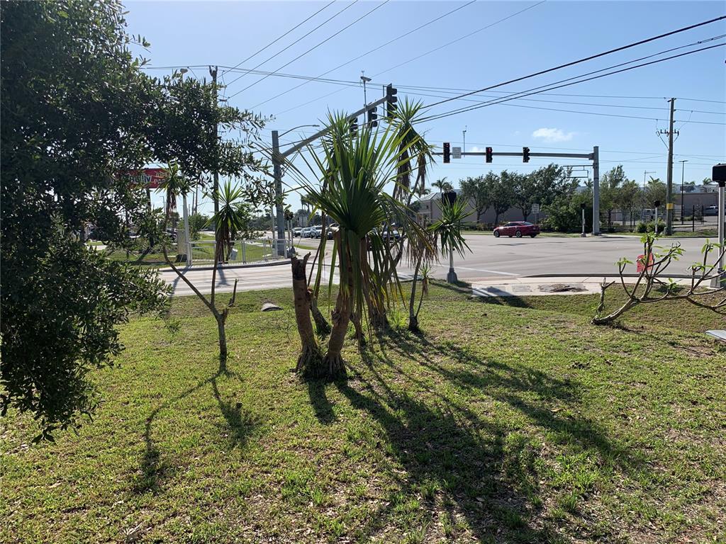 A grassy area with palm trees and shrubs sits in front of a road intersection — 23540 PEACHLAND BOULEVARD, PORT CHARLOTTE, FL
